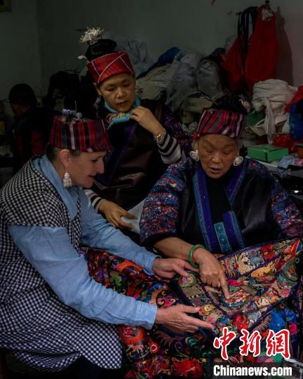图为潘玉珍老人向外国友人介绍苗绣。 受访者供图