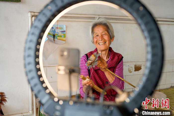 一位农村妇女正通过网络直播向网友展示鸡毛掸子制作过程。 赵亮 摄