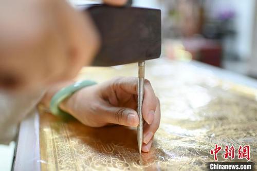 中国侨网饶宝莲展示铜凿剪纸敲打过程。 陈骥旻 摄