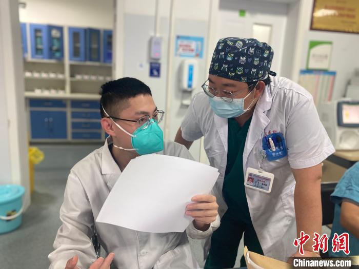 图为高岩捷(右一)和同事进行交接班工作。 张玮 摄